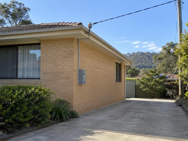 Brick house exterior with overhead service cable and point-of-attachment bracket near the roofline in Narara