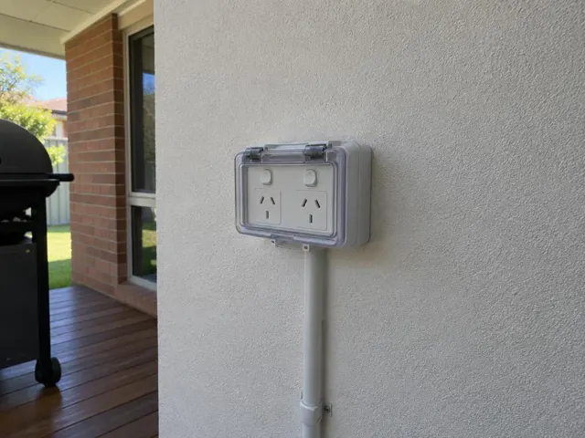 Outdoor double power point on a rendered exterior wall beside a patio in Wyoming